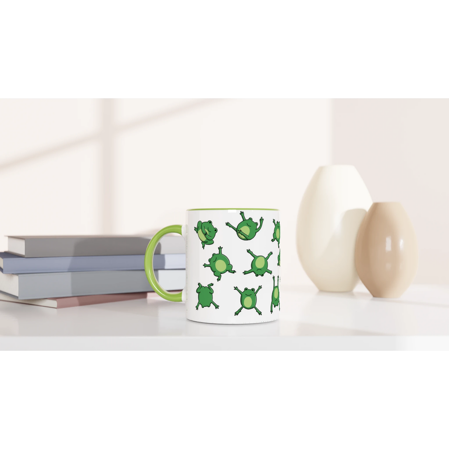 Astral Apple dish washer safe, microwave safe ceramic coffee mug in White and Green, with graphic print of lots of cute, smiling, cartoon style frogs , on a desk, for the person who loves frogs