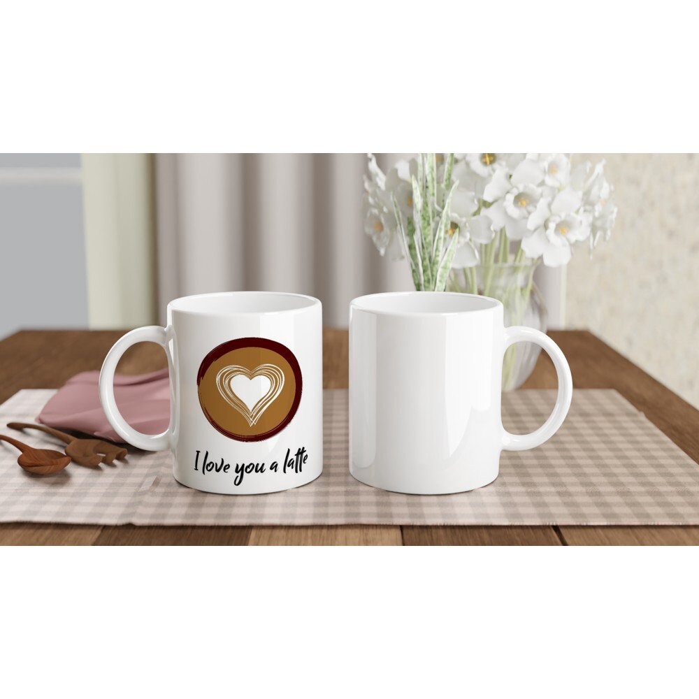 Front and back views of a white ceramic mug with the words "I love you a latte" in black and a top view of latte art with a heart.