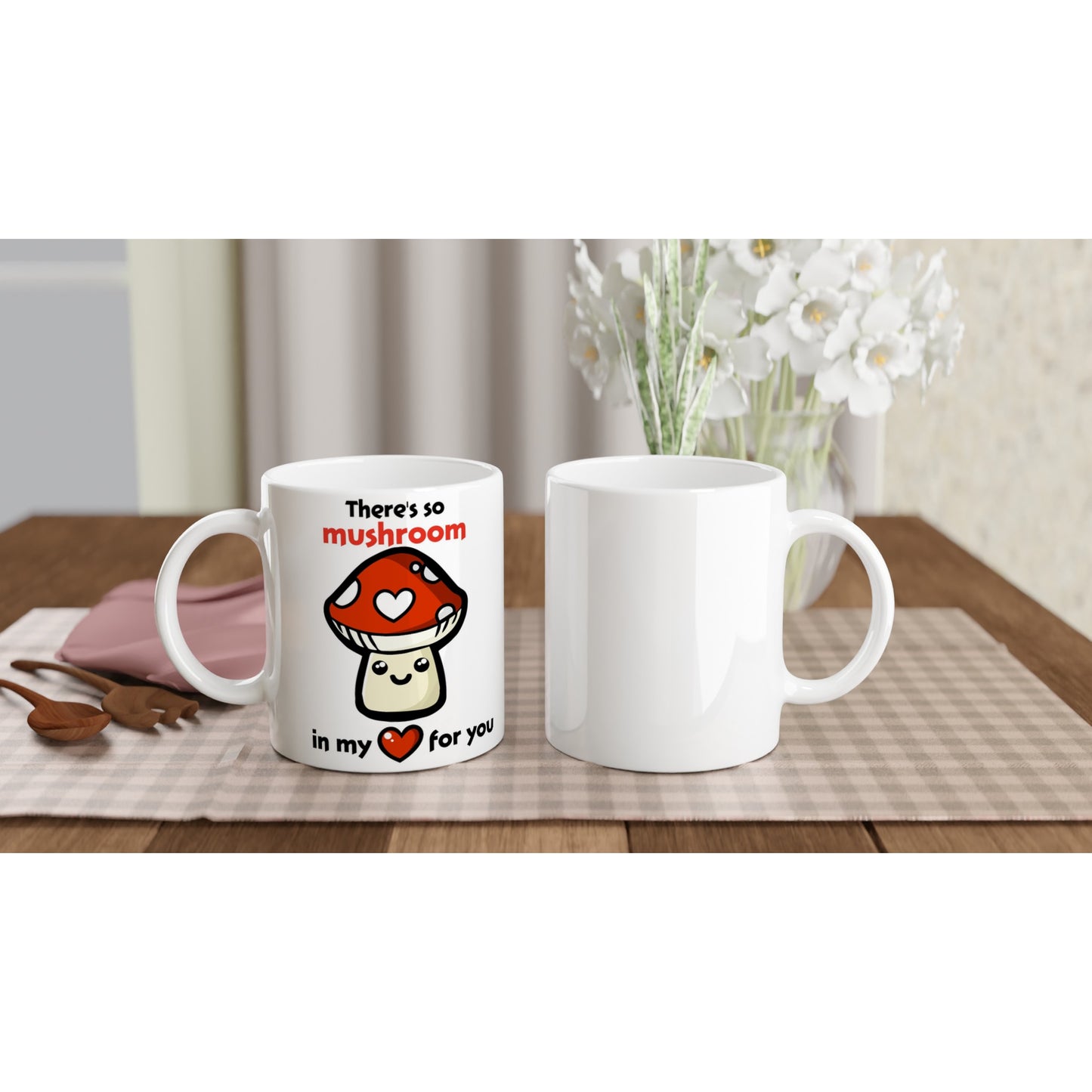 The front and back view of a white ceramic mug with black text saying, "There's so mushroom in my heart for you" where the word mushroom is in red and the word hear is replaced with a red heart, and there is a picture of a cute, smiling cartoon style amanita muscaria or fly agaric mushroom where one of it's white spots is a white heart.