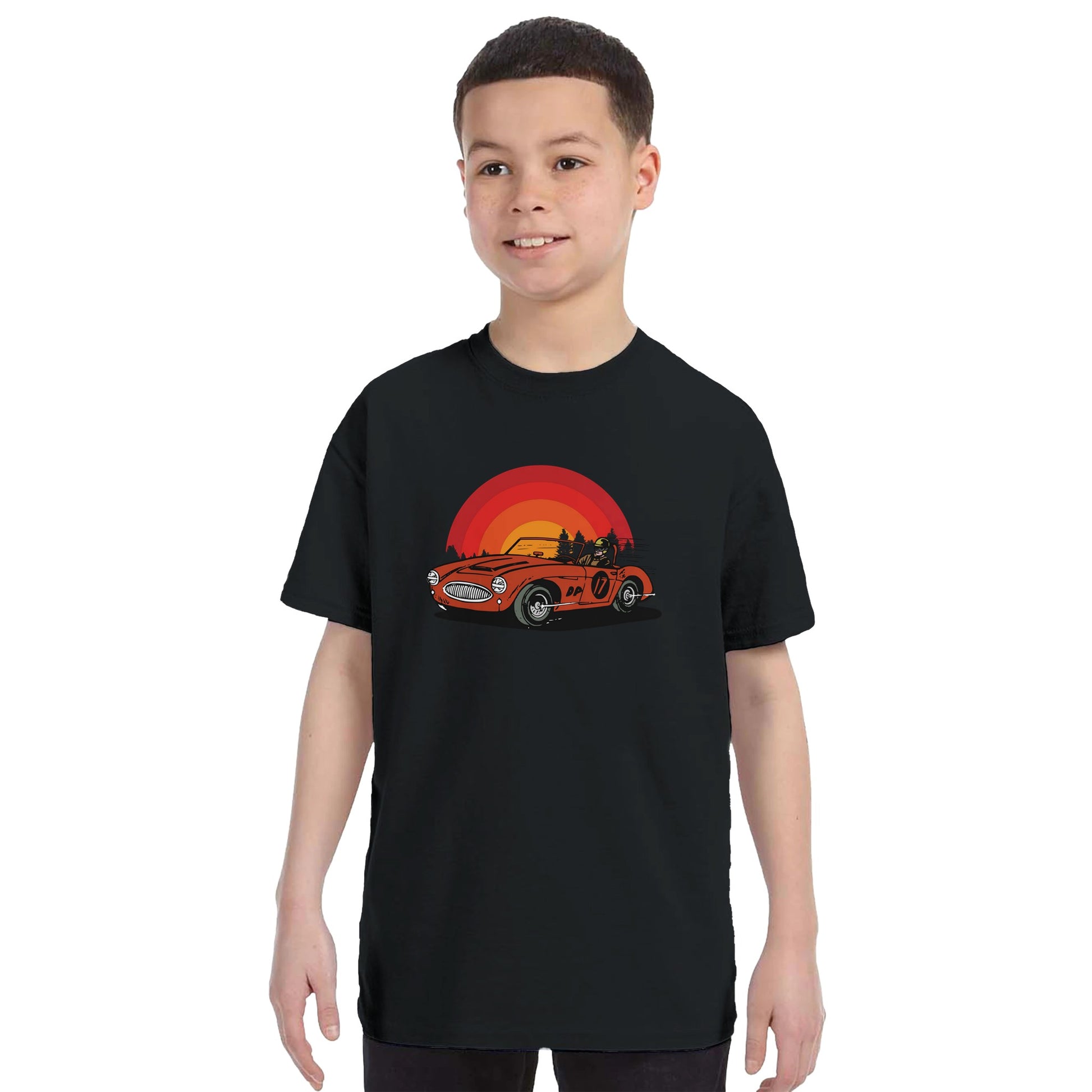 A kids black t-shirt with a car and sunset printed on it being worn by a child