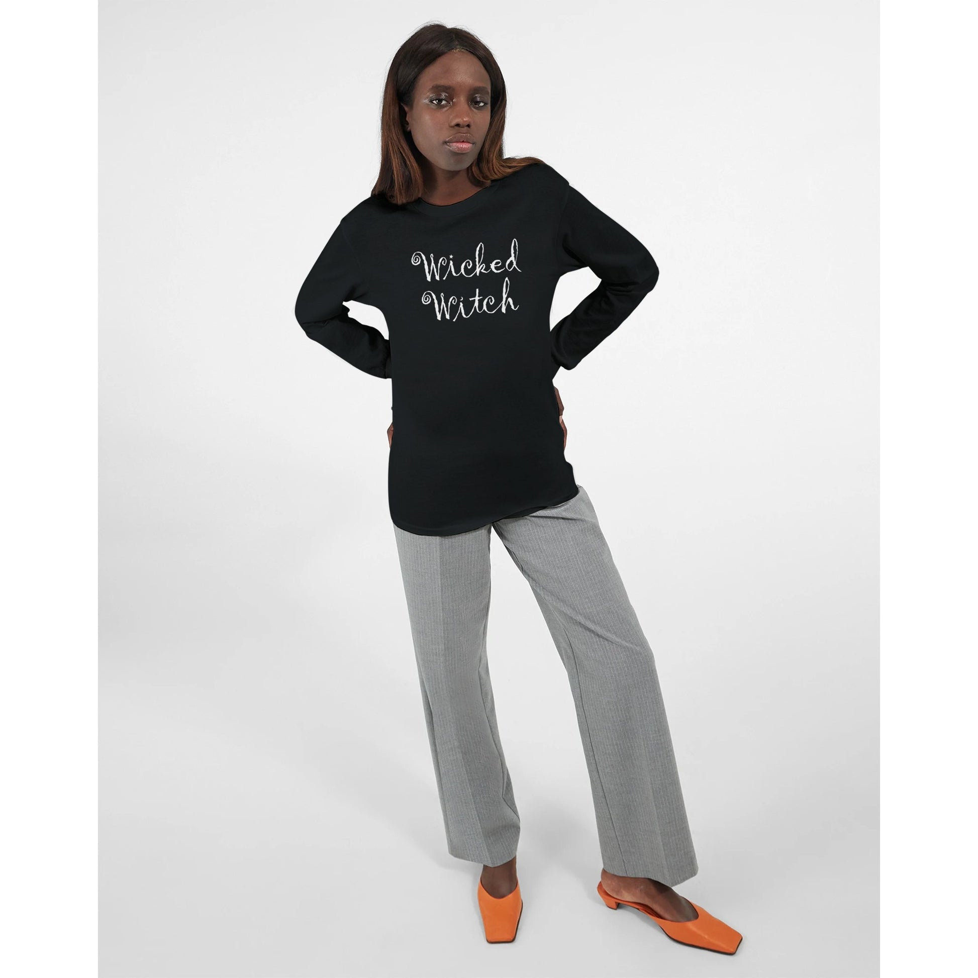 A black long sleeved t shirt for women with the quirky and curly text, "Wicked Witch" with a star and moon, worn by a woman.