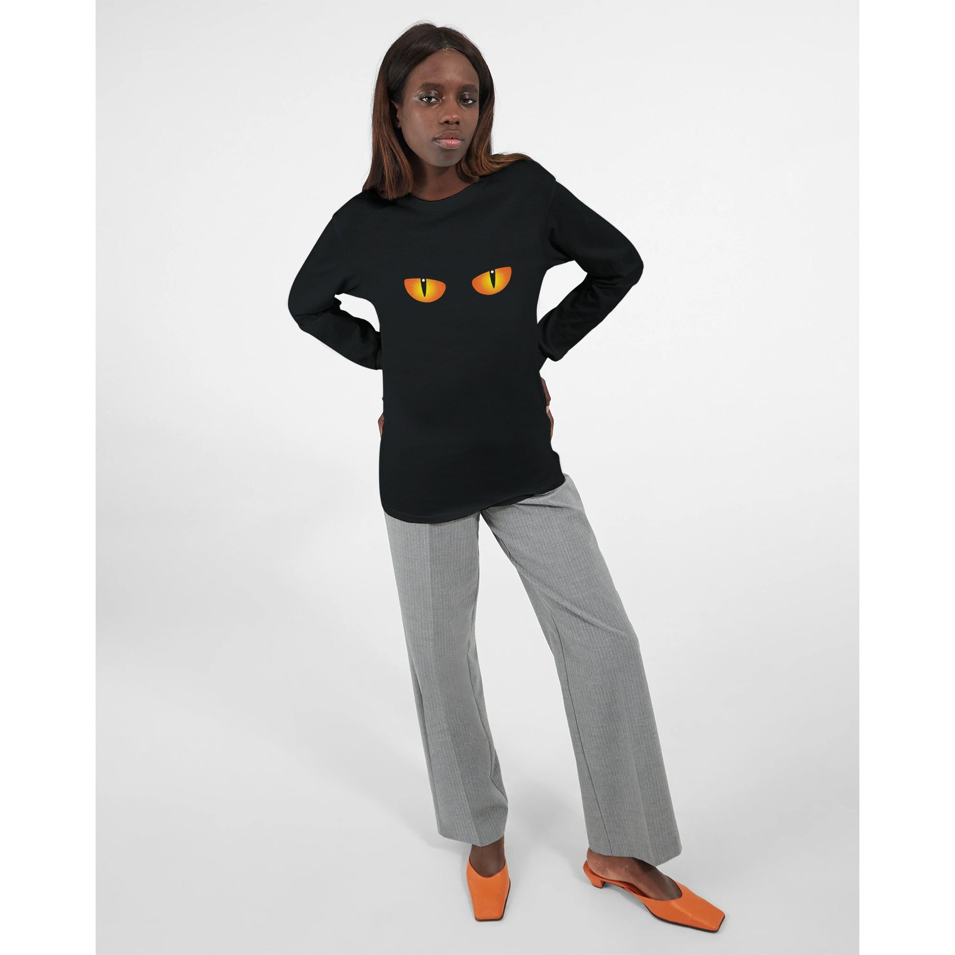 A black, long sleeved Halloween t shirt with a spooky cat's eyes worn by a woman.