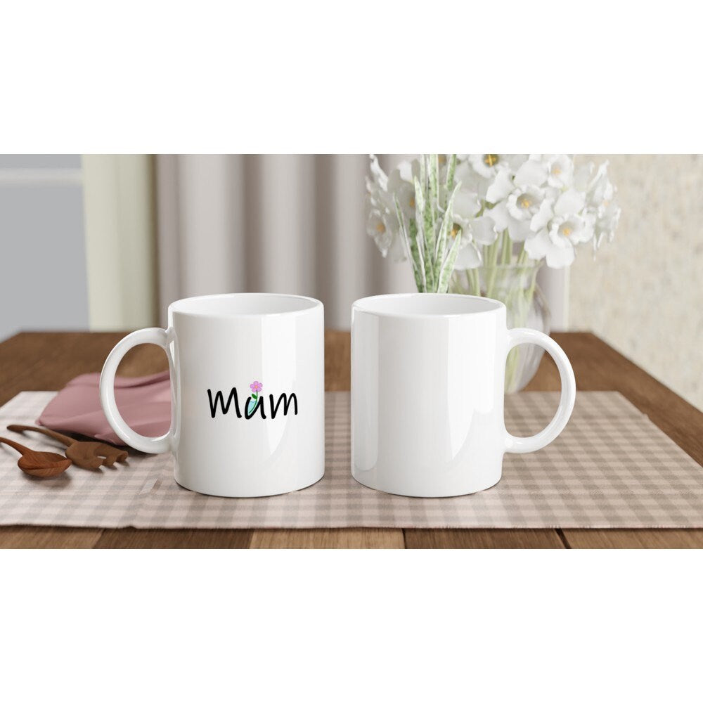 The front and back view of a white ceramic mug with the word, "Mum" written on it in black where the letter "U" is a container with water in it and a pink flower sticking out.