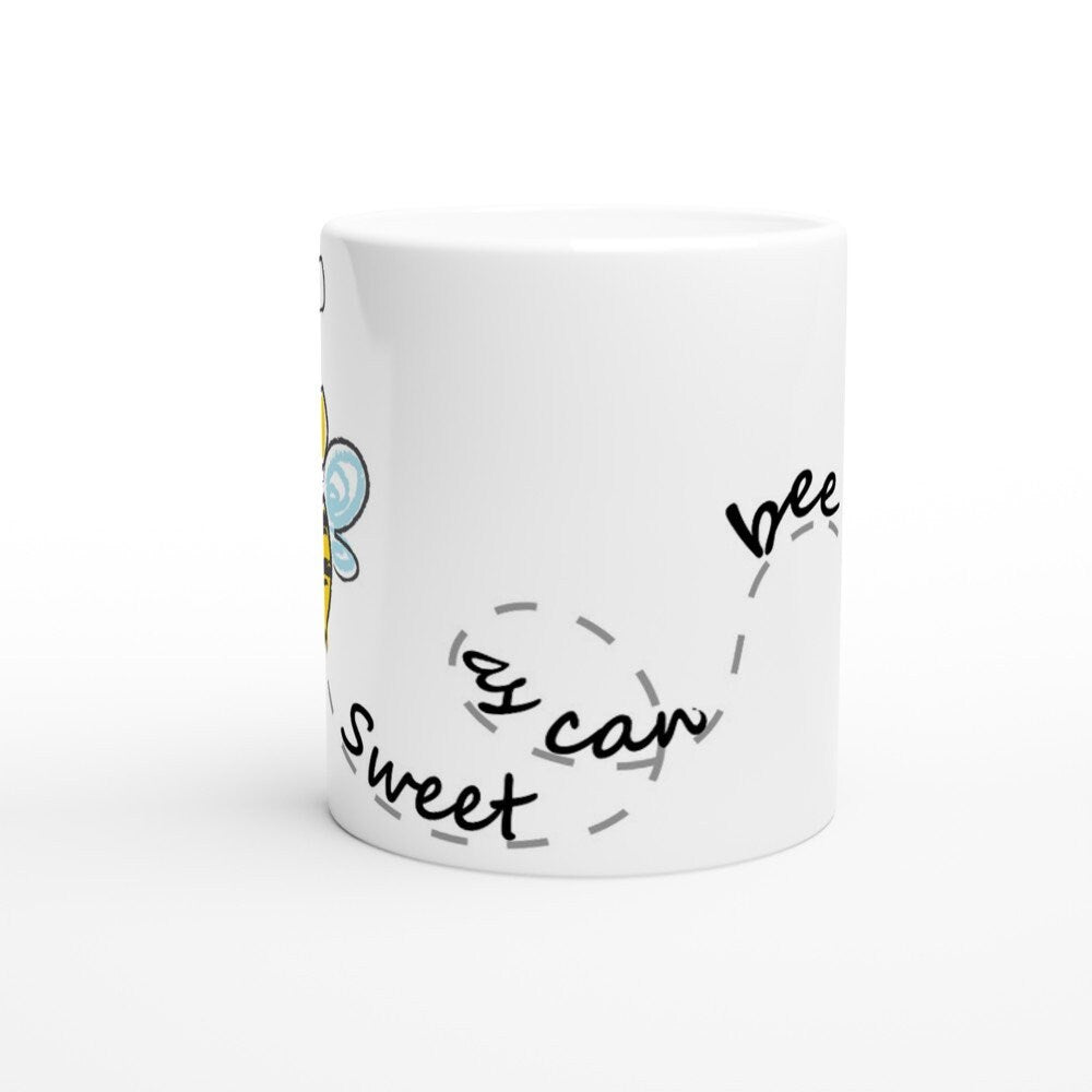 The side view of a white ceramic mug with black text saying, "Sweet as can bee" and the image of a drawing of a bee and it's path across the cup.