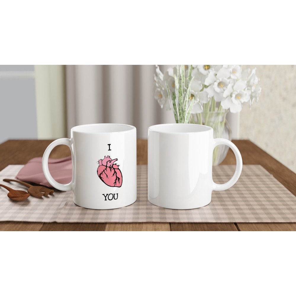 Front and back views of white ceramic mug with the words "I 'heart' you" in black, where the heart is an anatomically correct illustration of a heart