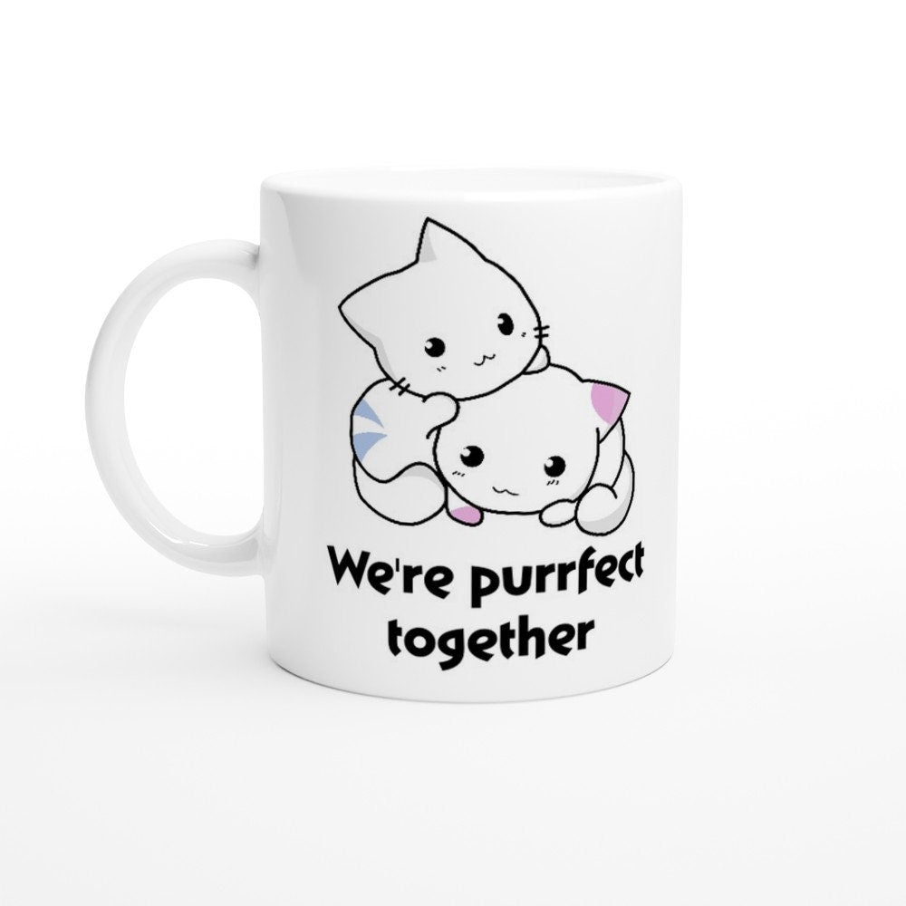 A white ceramic mug with the words, "we're purrfect together" and the image of a white and blue striped cat next to a white and pink spotted kitten