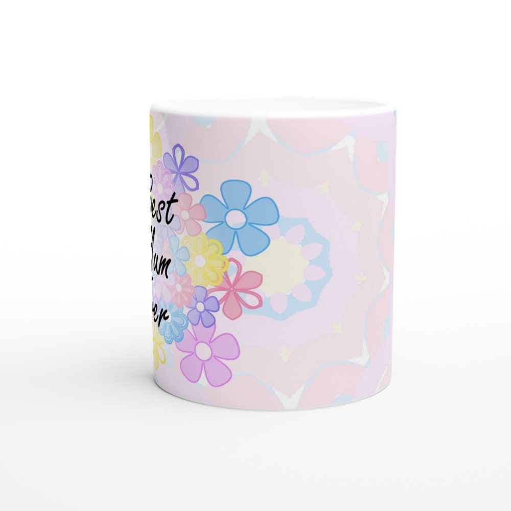 Side view of a white ceramic mug with the words "Best Mum Ever" written on it, with a background of pastel coloured flowers.